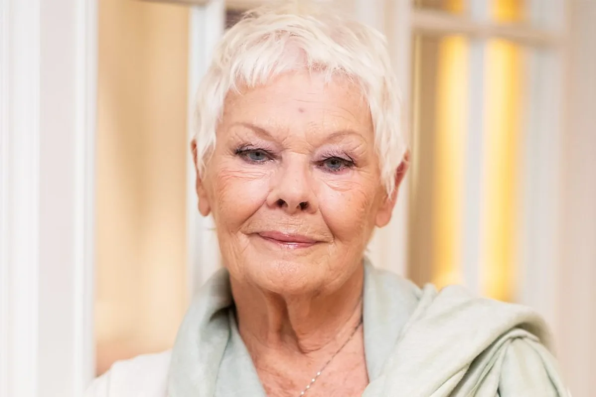 Portrait de Judi Dench aux cheveux courts et blancs, portant une étole vert pâle